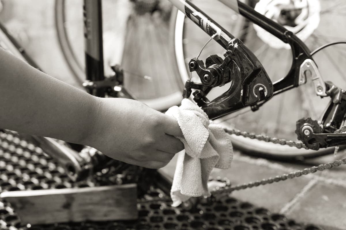 Hands cleaning a bicycle chain with a brush