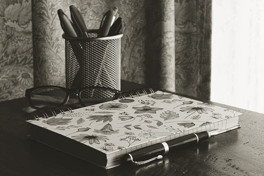 An open notebook and pen on a wooden desk