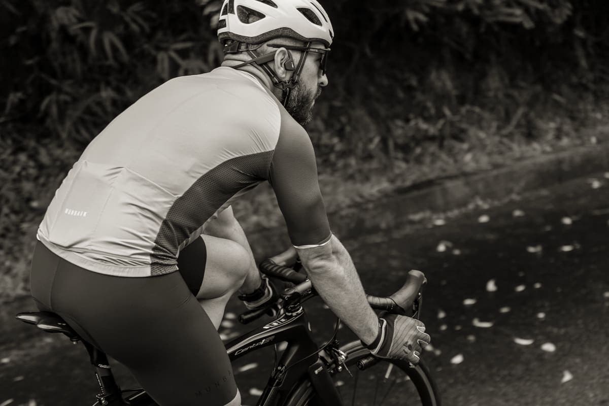 A cyclist in padded shorts and a jersey beside a bicycle