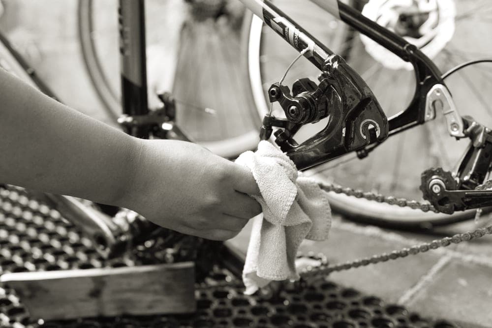 Hands cleaning a bicycle drivetrain outdoors